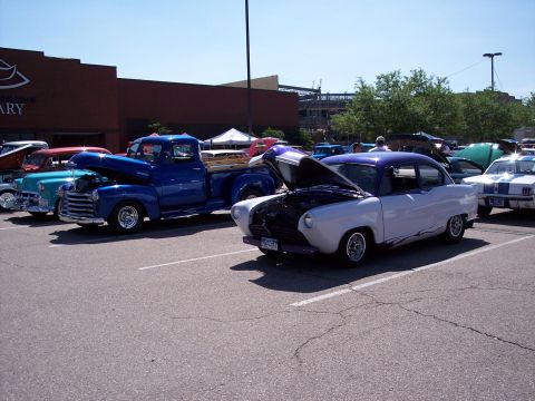 1972 Ford Ranchero - A car show features a variety of classic vehicles, including a blue pickup and a custom two-tone sedan.