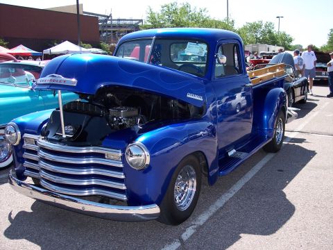 1972 Ford Ranchero - Customized blue Chevrolet pickup truck with flame graphics and exposed engine at an outdoor event.