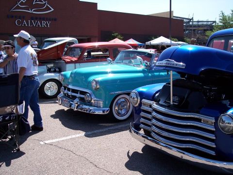 1972 Ford Ranchero - A car show features several vintage vehicles, with a blue Chevrolet and a turquoise convertible prominently displayed.