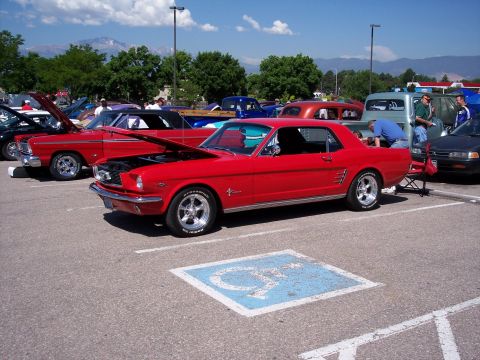 1972 Ford Ranchero - A red 1965 Ford Mustang coupe is parked in a lot, with its hood open, alongside other vehicles.