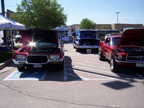 1972 Ford Ranchero - A red 1972 Ford Ranchero is parked with its hood open, alongside other vehicles at an outdoor event.