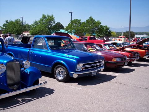 1972 Ford Ranchero - A line of cars are parked in a lot on a sunny day, with a bright blue pickup truck in the foreground.