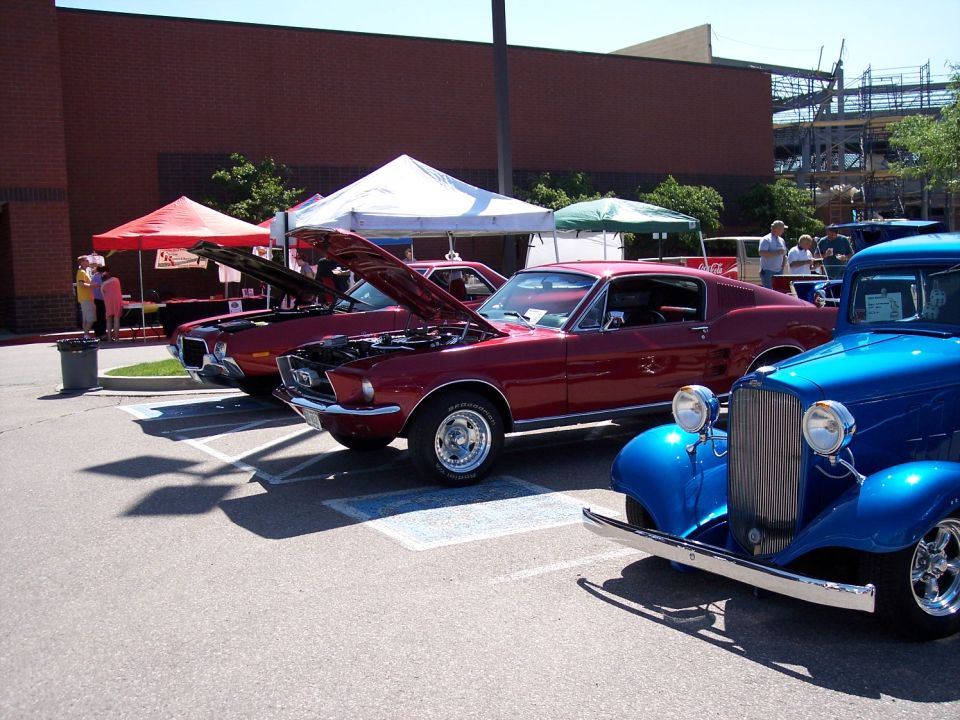 Red 1967 Ford Mustang coupe with hood open, parked next to a blue hot rod