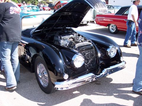 1972 Ford Ranchero - A black classic car is displayed with its hood open, its engine and chrome details, with other vehicles visible in the background.