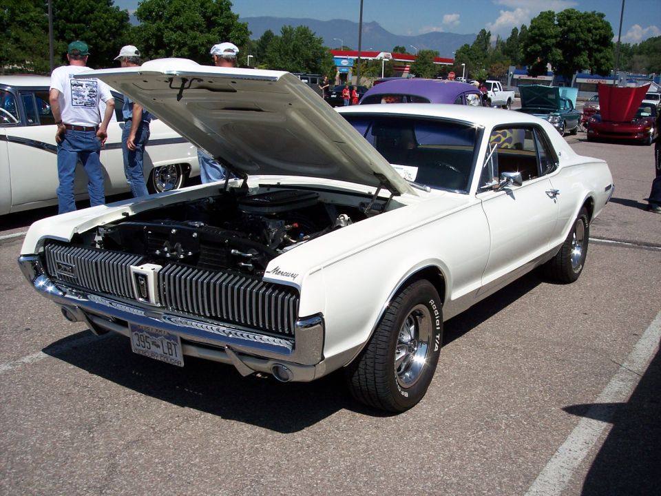 White 1968 Mercury Cougar with hood open, showing engine. Chrome grille and front bumper visible