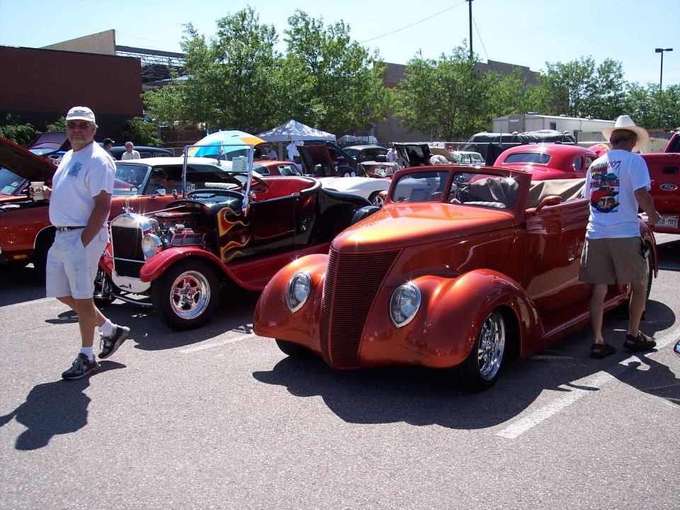 Orange custom hot rod convertible with chrome wheels and a tall grille