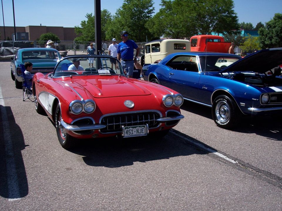 Red convertible with white side panels and a blue coupe with hood up parked on asphalt