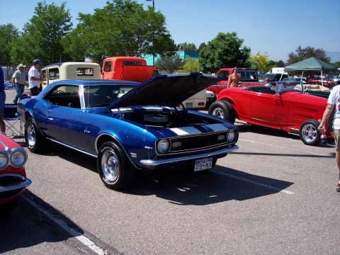 1972 Ford Ranchero - A blue 1967 Chevrolet Camaro is displayed with its hood open, alongside other vehicles at an outdoor event.
