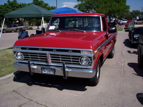 1972 Ford Ranchero - This red 1972 Ford Ranchero is parked at an outdoor event, showing off its distinctive front grille and chrome bumper.