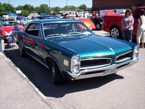 1972 Ford Ranchero - Teal green 1966 Pontiac Tempest coupe at a car show with other vehicles present.