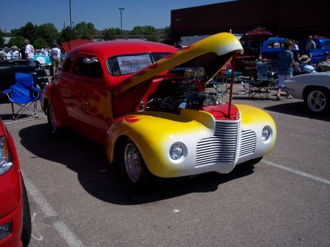 1972 Ford Ranchero - A custom hot rod with a bright red body, yellow fenders, and flame graphics is displayed with its hood open.