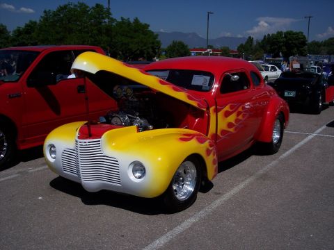 1972 Ford Ranchero - Custom hot rod coupe with flame paint and exposed engine, parked at an outdoor event.