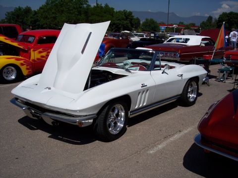 1972 Ford Ranchero - A white convertible sports car is parked with its hood open, alongside other vehicles.