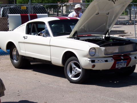 1972 Ford Ranchero - White 1965 Ford Mustang with red stripes, hood open, parked outdoors.