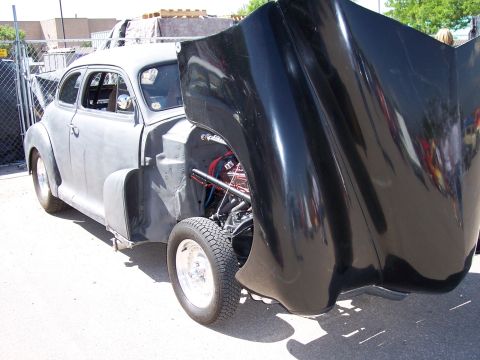 1972 Ford Ranchero - A car with its hood open reveals its engine and a black fender, parked outdoors.