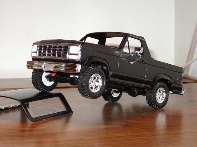 Black model truck with chrome grille and wheels. Removable roof is in the foreground