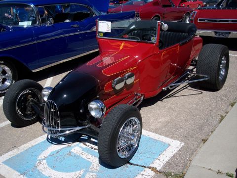 1972 Ford Ranchero - A custom red hot rod with a black hood and flame decals is parked next to a blue classic car.