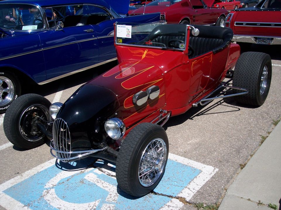 Red hot rod with black hood and yellow flames, wire wheels, parked in a handicapped spot