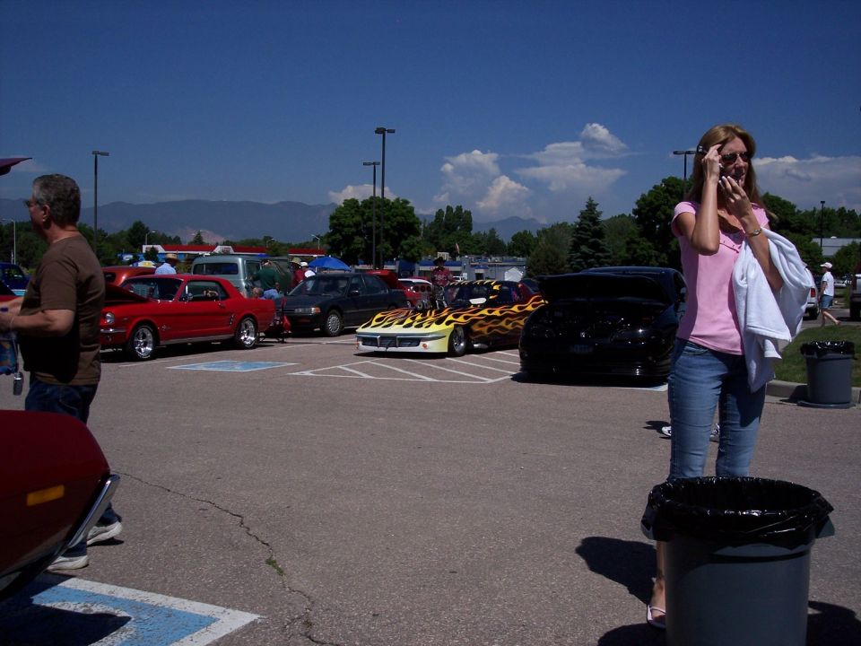 Cars with flame decals and a red Mustang at a car show