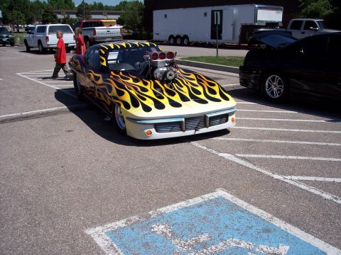 1972 Ford Ranchero - A heavily modified hot rod with a prominent supercharger and flame paint job is parked in a lot.