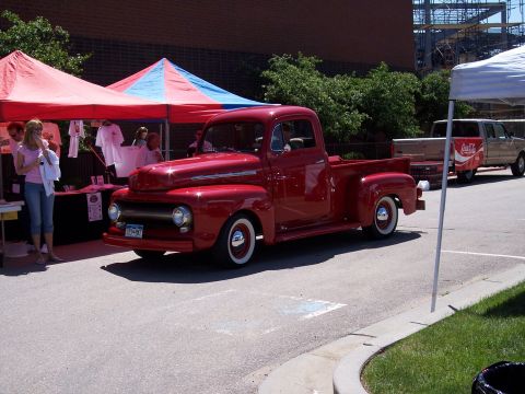 1972 Ford Ranchero - A classic red Ford pickup truck is parked near tents, with another vehicle visible in the background.