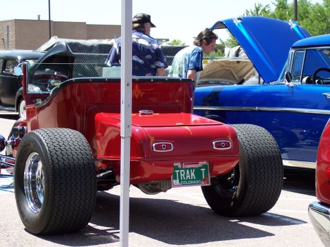 1972 Ford Ranchero - A red hot rod with custom pinstriping and wide rear tires is parked next to a blue classic car.