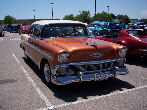 1972 Ford Ranchero - A two-tone orange and white 1956 Chevrolet sedan is parked in a lot next to a red sports car.