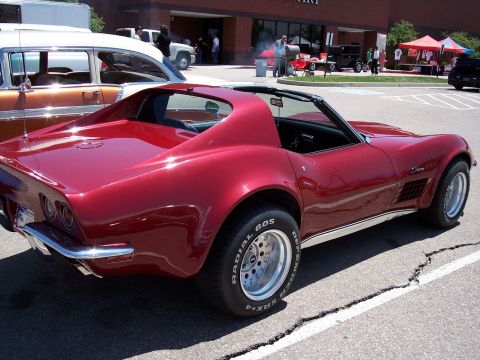 1972 Ford Ranchero - A shiny red 1970s Chevrolet Corvette is parked in a lot, with another classic car visible to the left.