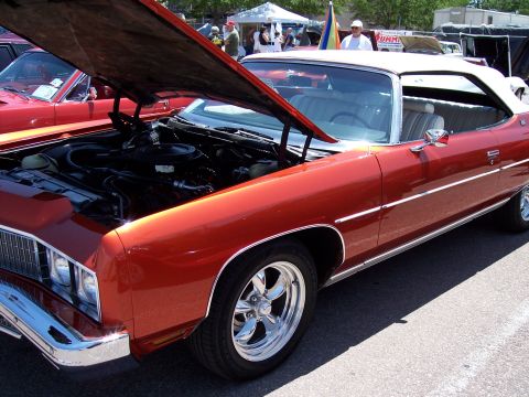 1972 Ford Ranchero - This orange convertible, likely a 1972 model, is displayed with its hood open, revealing the engine bay and chrome wheels.