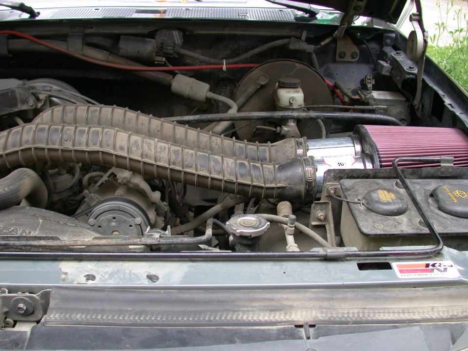 Engine bay of a 1993 Ford Bronco with aftermarket K&N cone air filter intake and factory ribbed intake hose