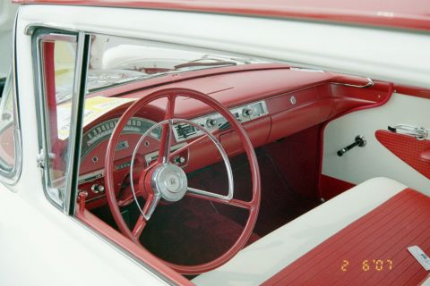 1976 Ford Ranchero - The interior of a classic car features a red steering wheel and matching dashboard with white accents.