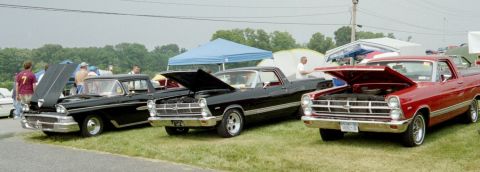 1976 Ford Ranchero - Three vintage pickup trucks are displayed with their hoods open at an outdoor event.