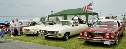 1976 Ford Ranchero - Several classic vehicles are displayed outdoors under a tent, with an American flag flying.