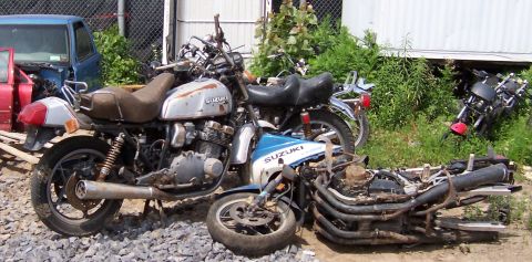 1980 Jeep CJ5 - Junkyard scene with multiple Suzuki motorcycles, some intact and others in pieces.