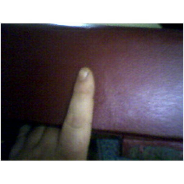 Finger pointing at a dark red textured surface, possibly interior upholstery
