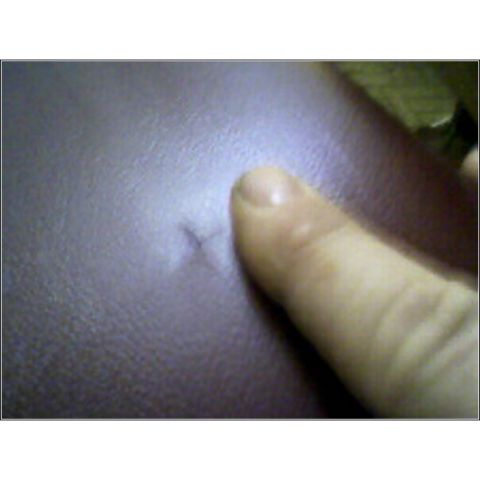 1973 Ford Ranchero - Close-up of a finger touching a small rip in the interior trim material.