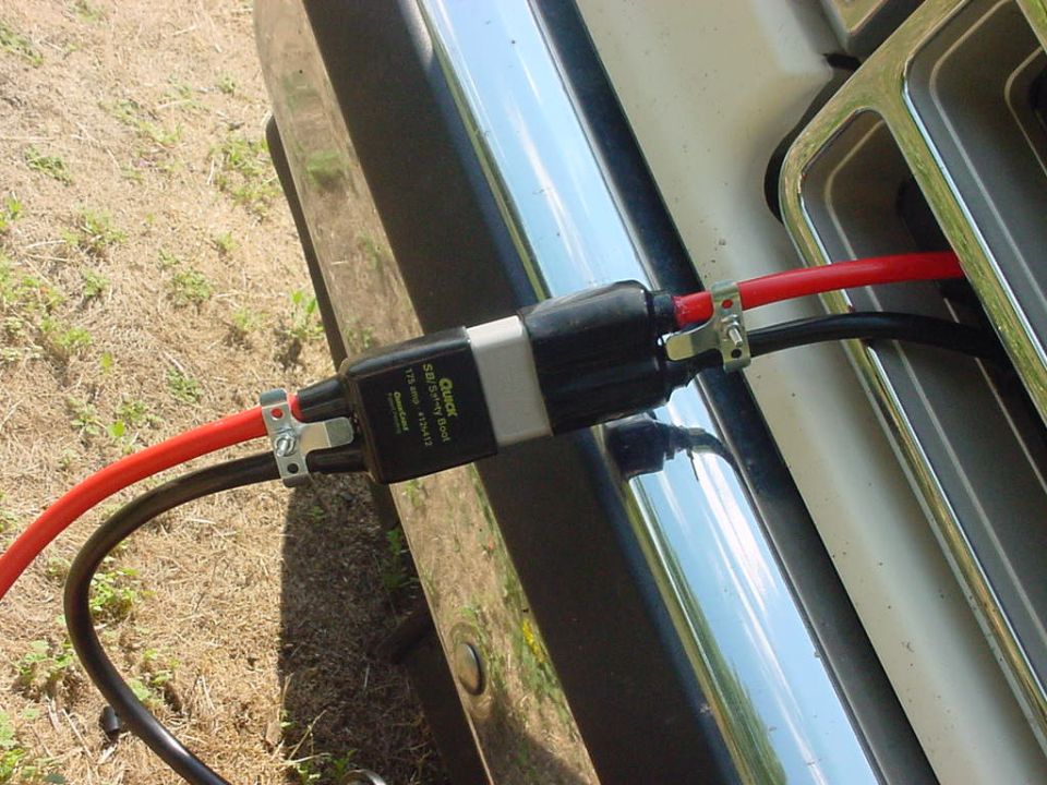 Quick-disconnect connector with red and black heavy cables mounted at the front bumper near a chrome grille