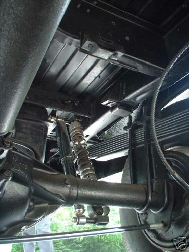 1978 Ford E250 - Close-up of the rear axle and suspension system of a vehicle, showing leaf springs and shock absorbers.