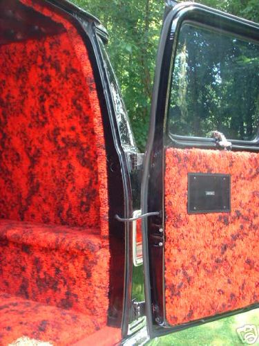 1978 Ford E250 - Interior view of a van with custom red and black patterned carpet lining the door panel and seat.