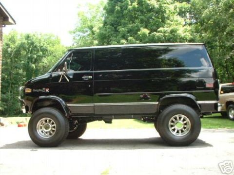 1978 Ford E250 - This black 1978 Ford E250 van features a lifted suspension and large off-road tires, giving it a commanding presence.