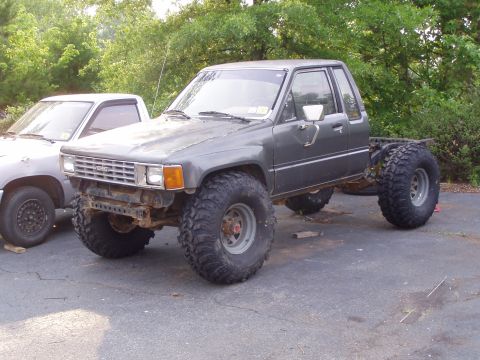1989 Ford F-250 - This modified Toyota pickup truck has been lifted with oversized tires and appears to be undergoing modifications or repairs.