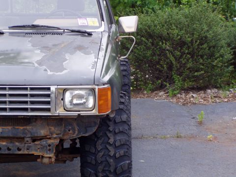 1989 Ford F-250 - A gray truck's front corner is visible, showing its large tires and a chrome grille.