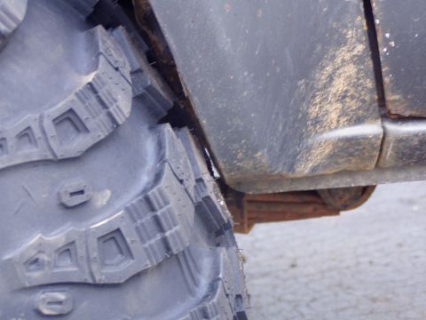 1989 Ford F-250 - A close-up view shows a large off-road tire positioned near the fender and leaf spring of a vehicle.