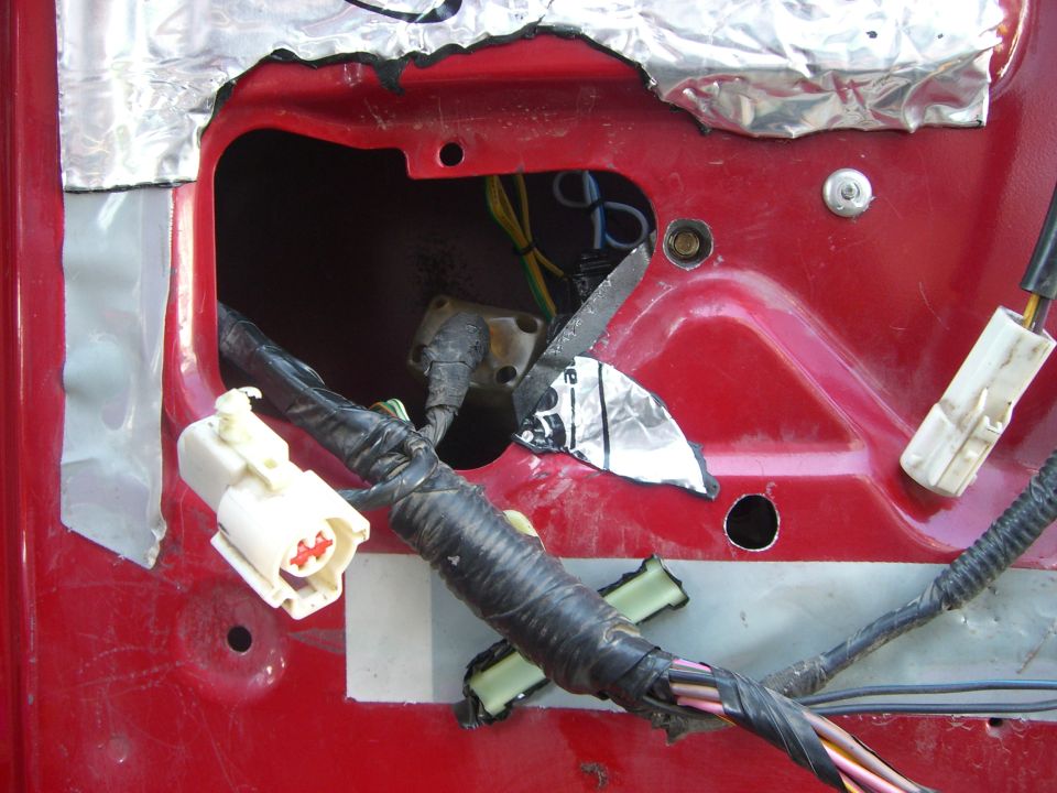 Red Bronco door with panel removed showing access hole, foil tape, and wiring harness connectors