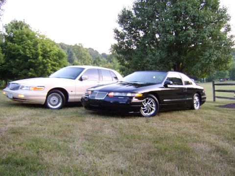 1996 Mercury Grand Marquis - A cream 1996 Mercury Grand Marquis and a black 1996 Lincoln Mark VIII are parked on a grassy lawn.