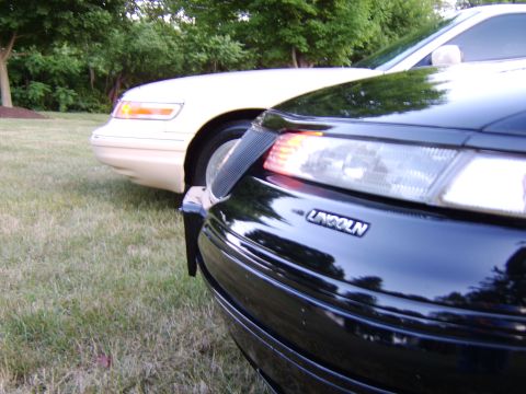 1996 Mercury Grand Marquis - Two sedans, a black Lincoln and a cream-colored one, are parked on a grassy area.