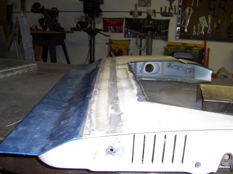 1991 Ford Bronco - A car's hood and fender are undergoing repair and modification in a workshop environment.