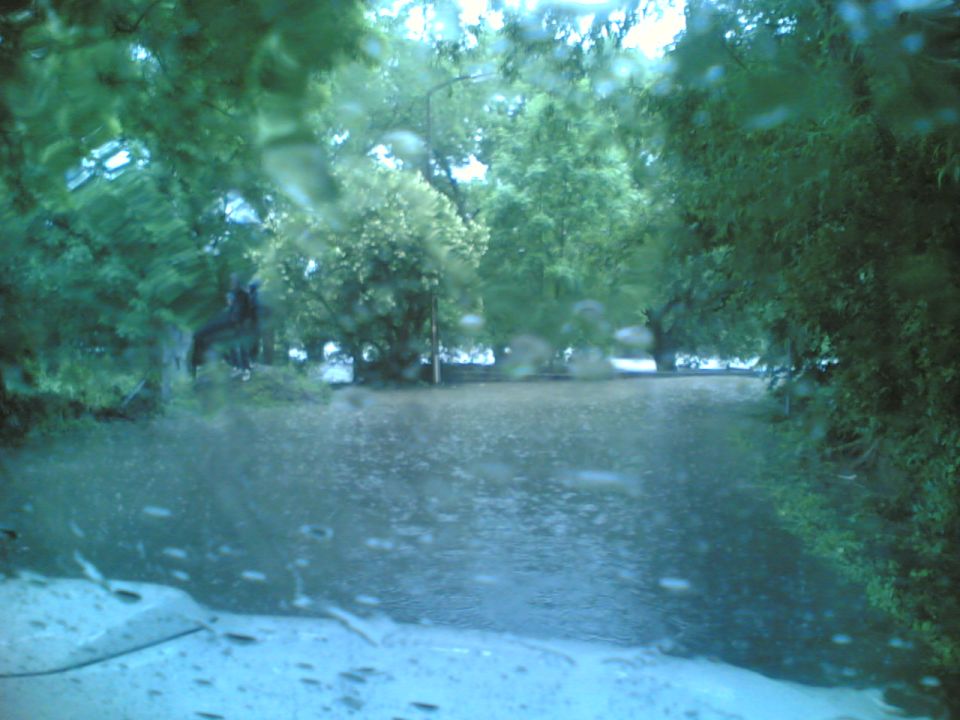 flooded road with trees and rain drops on windshield, supermotors.net logo