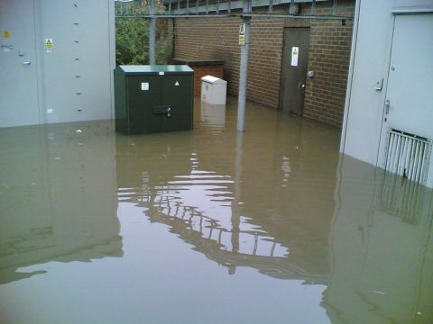 2001 Ford Fiesta - An industrial area is submerged in floodwaters, with electrical equipment partially underwater.
