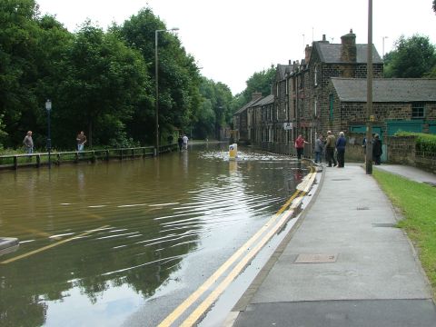 2001 Ford Fiesta - A street is flooded, with people observing from the sidewalk and wading through the water.
